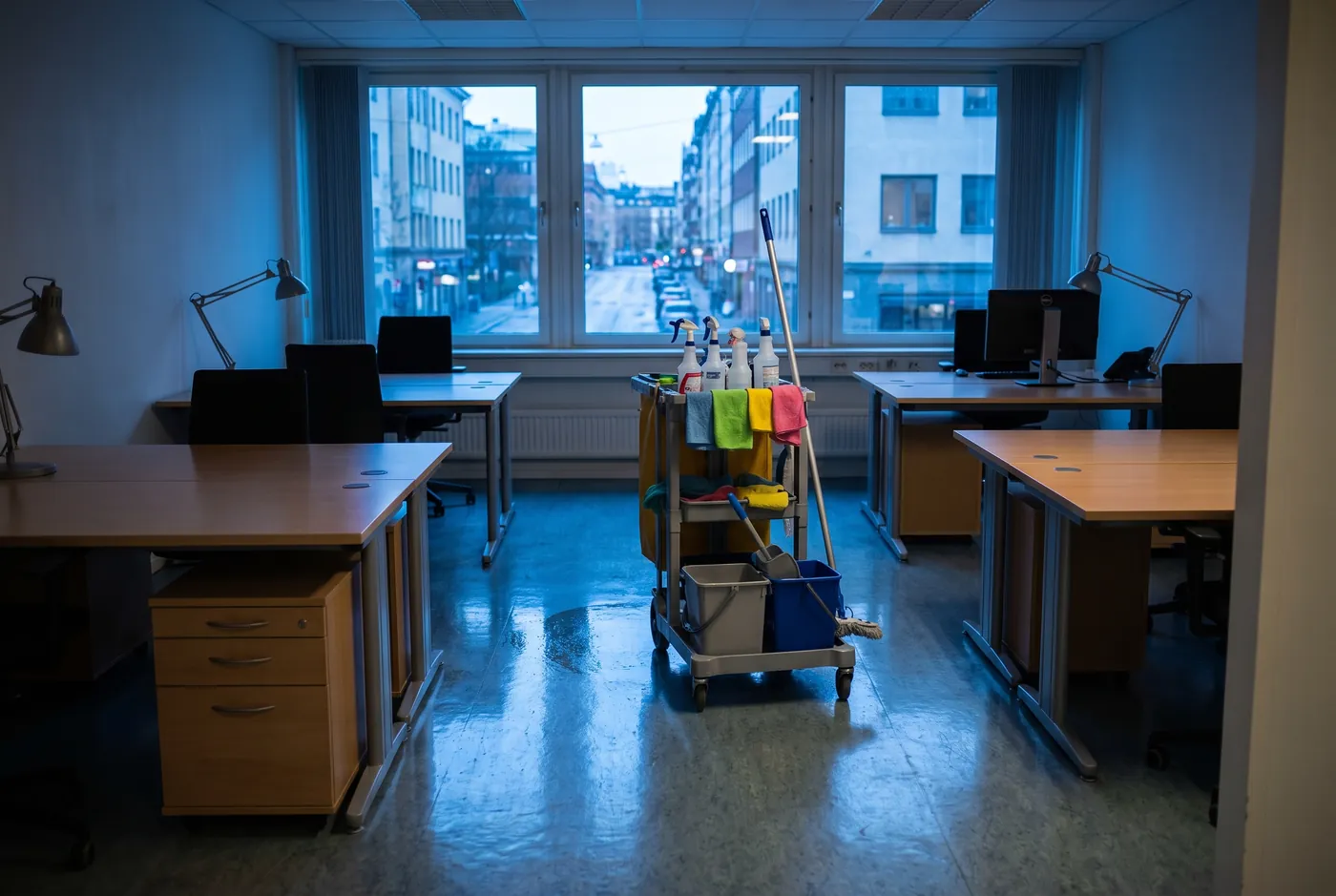 An empty office after hours with a cleaning cart and a freshly mopped floor