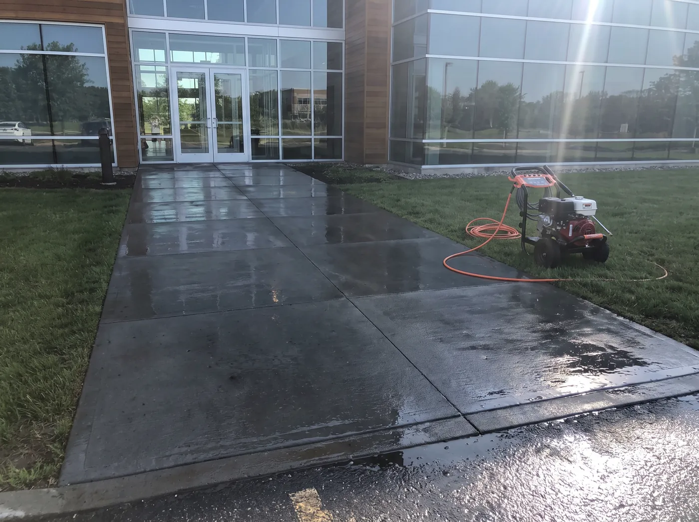 A freshly pressure washed concrete walkway at a commercial building entrance